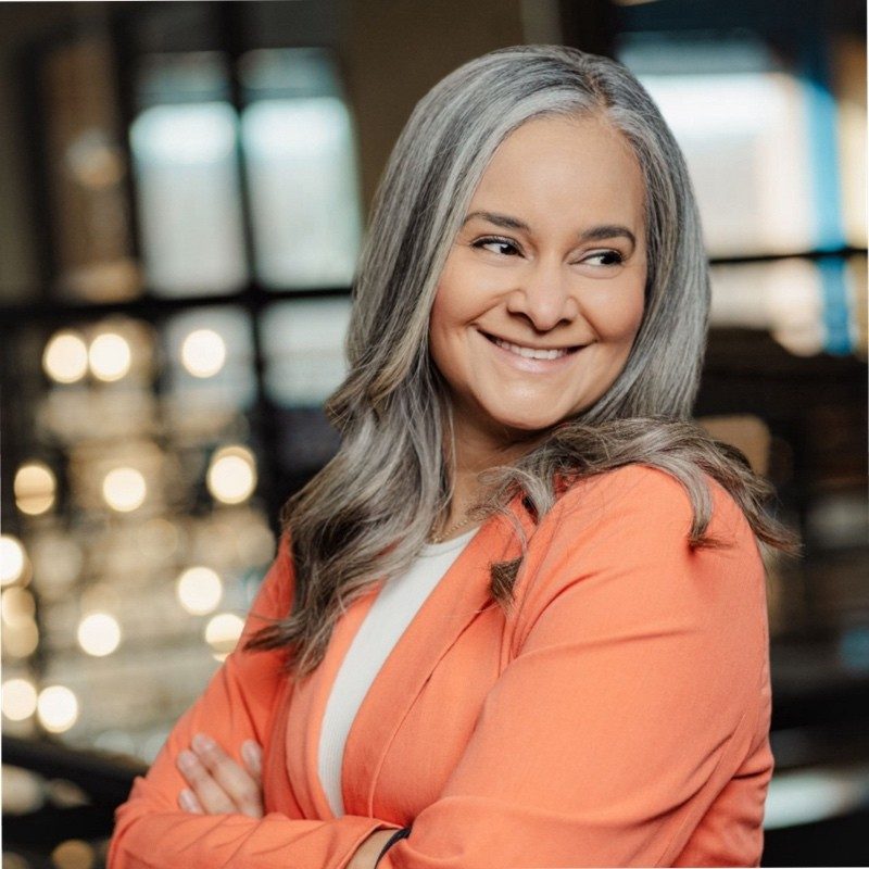 Dalia, multifamily speaker and AI trainer, smiling in a coral blazer